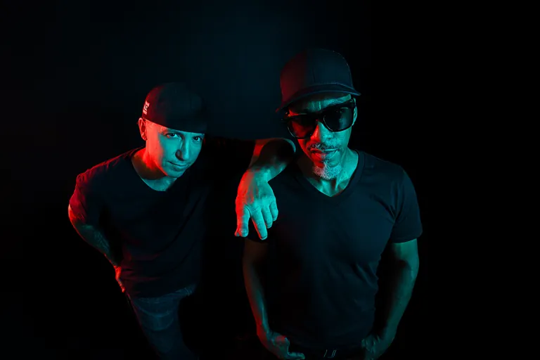The duo under red and blue studio lighting